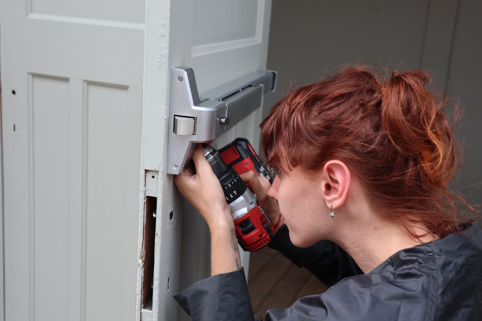 A technician drilling to fit a panic bar on a door