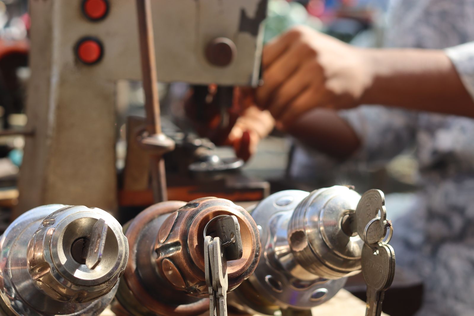 Hands working at a key machine with lock cylinders in front of them